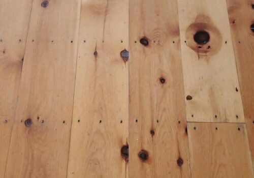 Wide plank flooring made from Eastern White Pine, showcasing natural knots and grain patterns, ideal for rustic interior spaces.