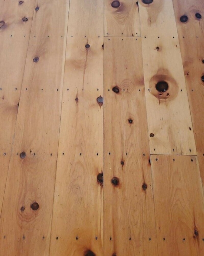 Wide plank flooring boards with natural knots and grain patterns for interior or outdoor decking.