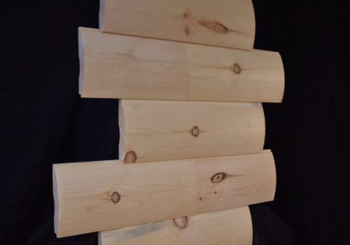 Precision-milled logs stacked, showcasing natural wood grain and knots, ideal for rustic construction projects like cabins and treehouses from Estemerwalt Lumber Products.