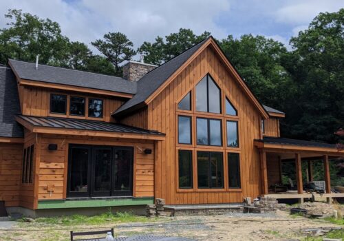 Modern rustic home featuring log siding and large windows, showcasing Estemerwalt Lumber's quality building materials in a natural setting.