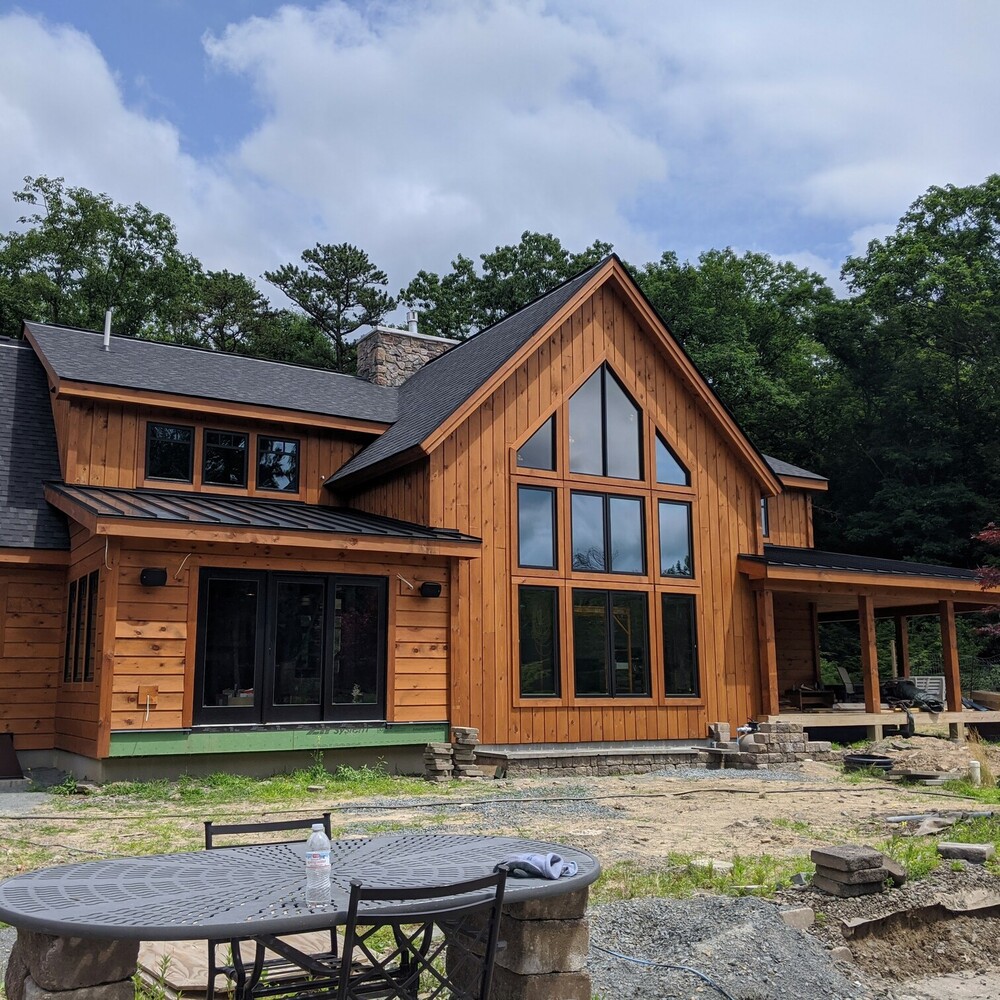 Two-story house with vertical wood siding, a tall gable of windows and a covered porch