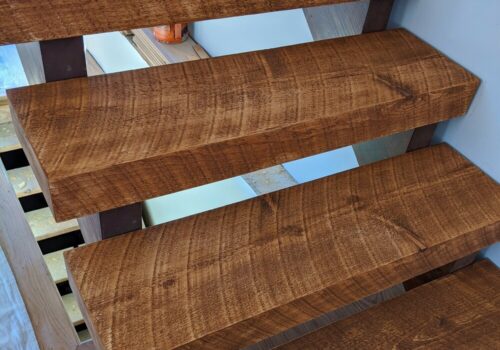 Sturdy wooden stairs showcasing rich, textured planks, emphasizing Estemerwalt's specialty lumber products for interior design.