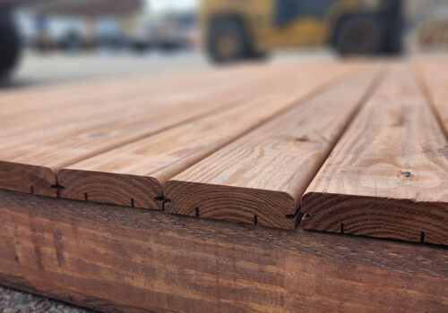 Close-up of KDAT Brown Decking with visible grooves for hidden fastener systems, showcasing rich wood texture and color, highlighting its pre-finished quality for easy installation and durability.