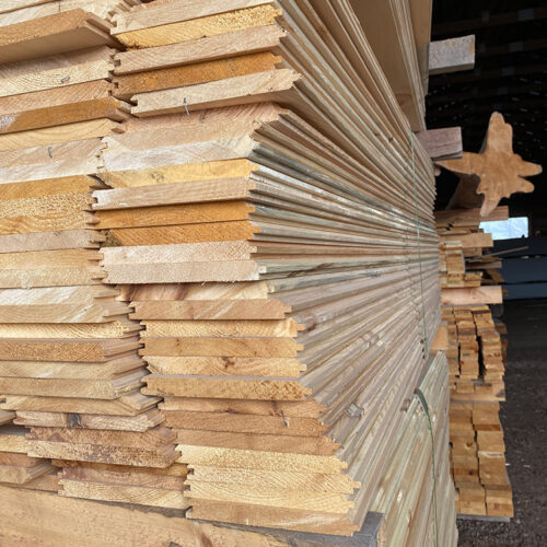 Stack of high-quality lumber boards, showcasing tongue and groove profiles, in a lumber yard setting at Estemerwalt Lumber Products, Honesdale, PA.