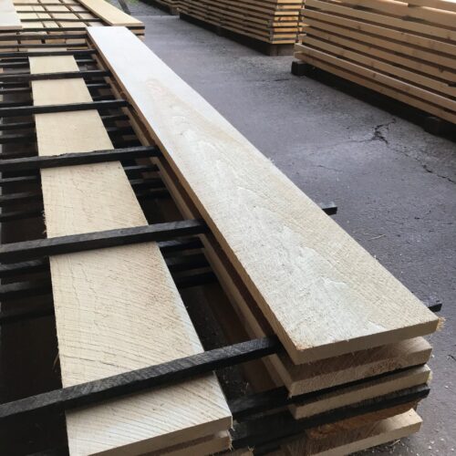 Clear rough-cut lumber stacked on metal racks at Estemerwalt Lumber Products, showcasing high-quality materials for residential and commercial projects in Honesdale, PA.