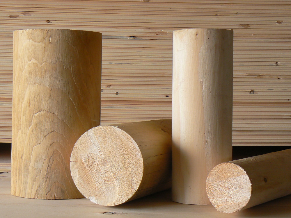 Logs and round wood products displayed against a wooden backdrop, emphasizing high-quality lumber for log home construction.