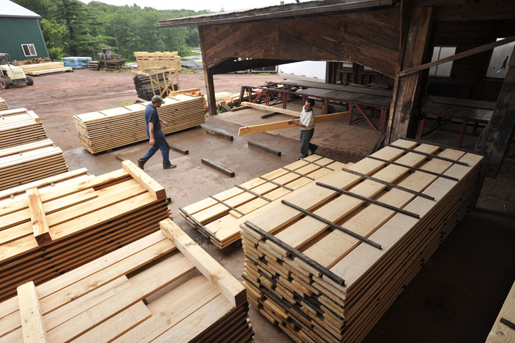 Workers handling lumber in a lumber yard, showcasing stacks of high-quality wood products for construction and home projects.