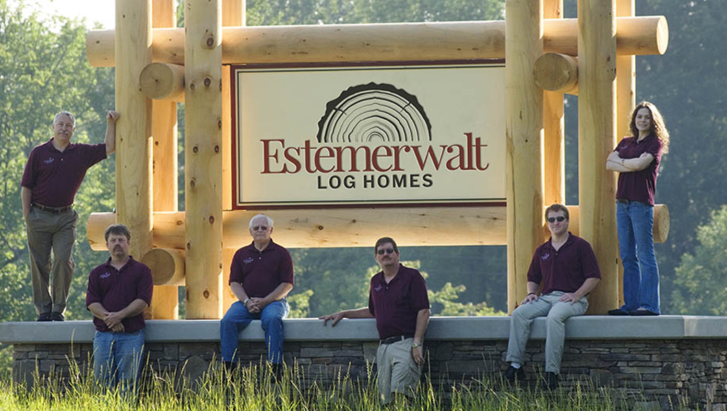 Estemerwalt Lumber team members posing in front of the Estemerwalt Log Homes sign, showcasing family-owned craftsmanship and commitment to quality lumber products in Honesdale, PA.